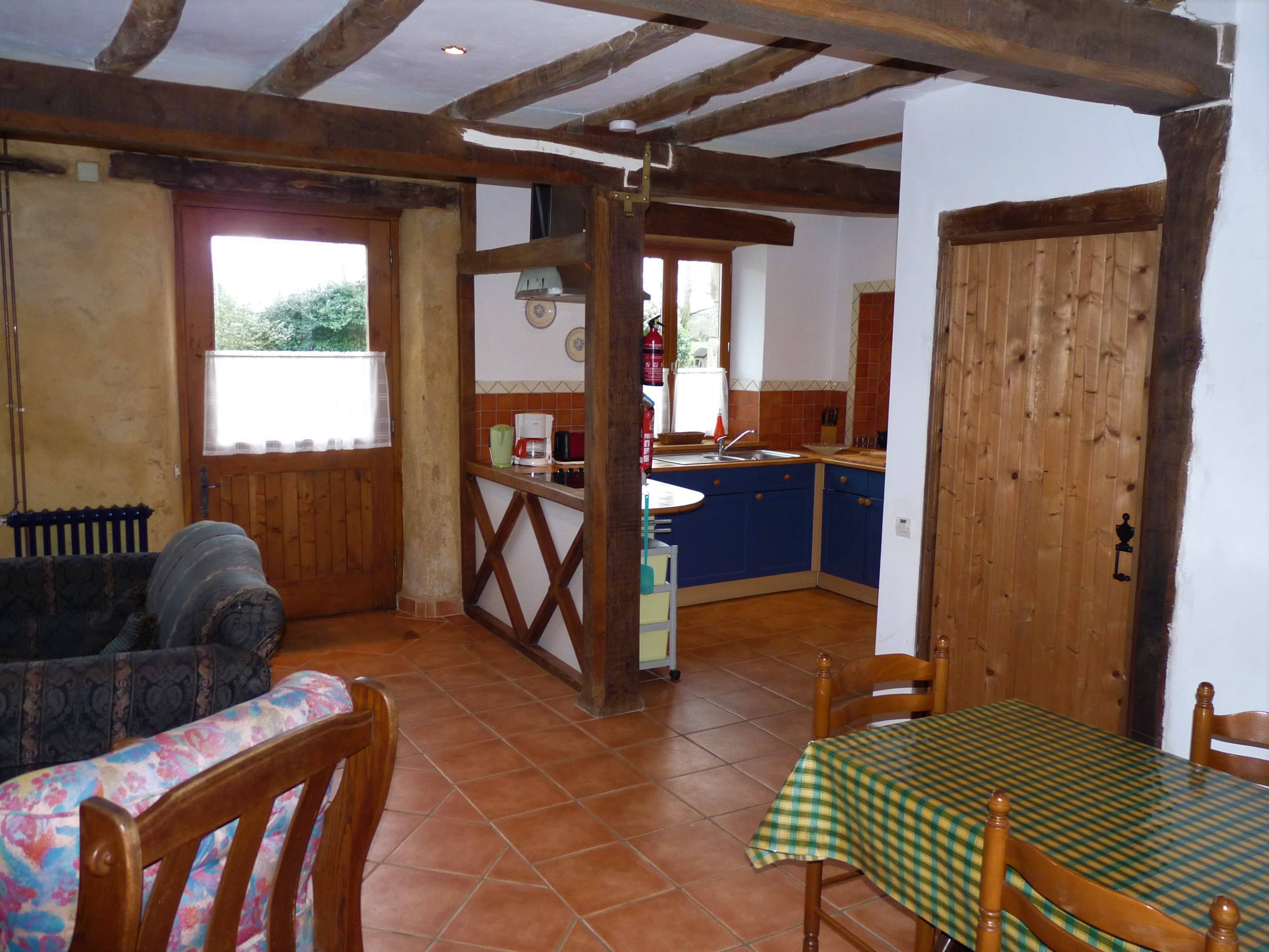 Bright and spacious dining room of La Julerie cottage in Brittany, France, featuring a large wooden table, comfortable chairs, and a fireplace. The room is beautifully decorated with rustic elements and offers stunning views of the surrounding countryside. Perfect for enjoying meals with family or friends during a holiday in Brittany.